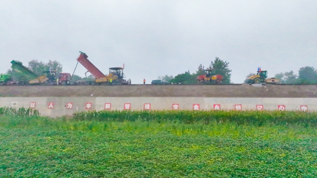 9月12日下午5时许，在涡蒙高速县城通攻坚现场，工人们冒着蒙蒙细雨摊铺水稳。这个中秋节，建设者们仍坚守一线，全力攻坚.jpg